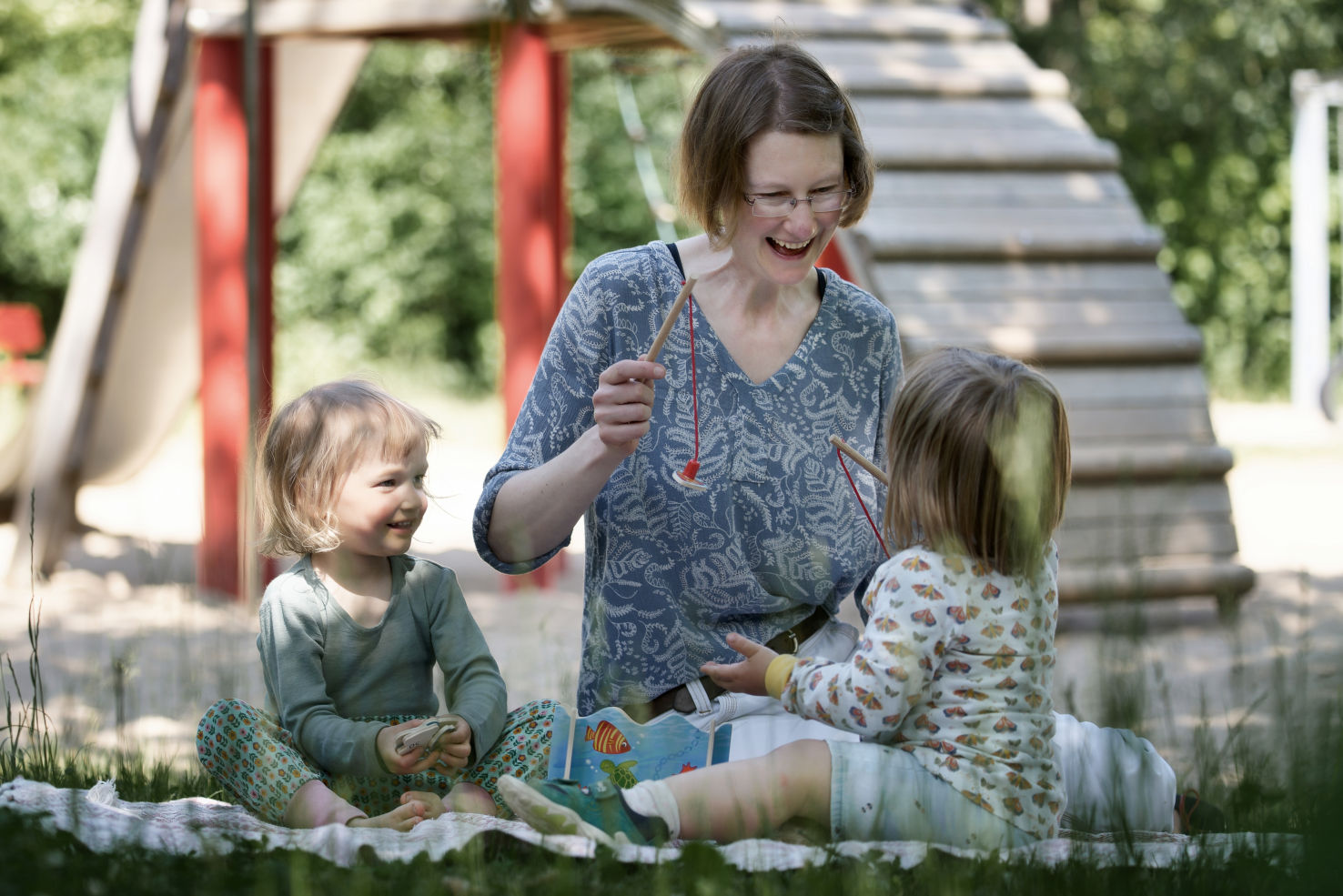 Sonja Niklesz spielt draußen mit zwei Kindern ein Angelspiel